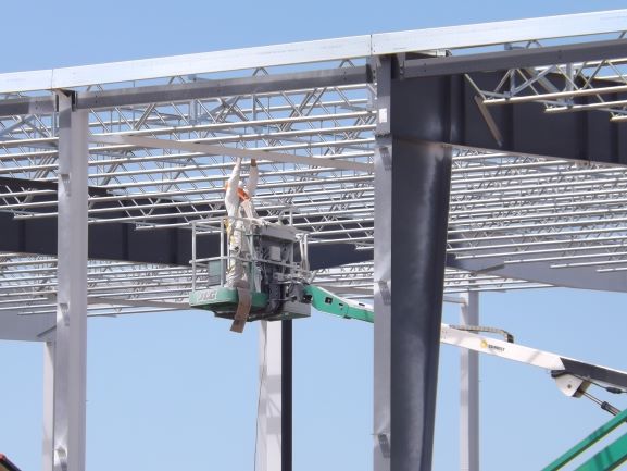 Construction Worker on Elevated Platform Working on Roof of Steel Building Framework