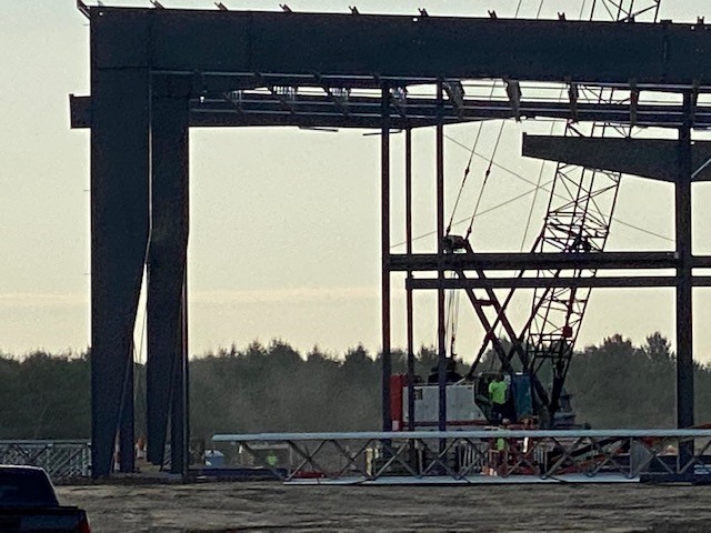 Close-up of warehouse steel structure progress and crane operator