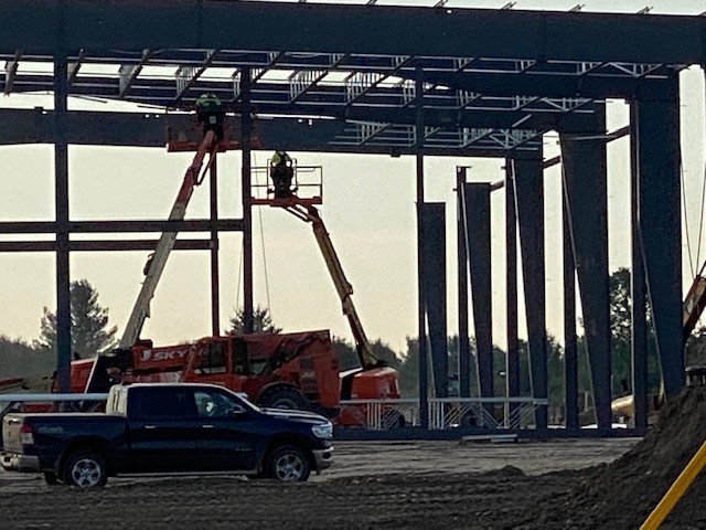 Close-up warehouse structural steel -worker on raised hydraulic lift.